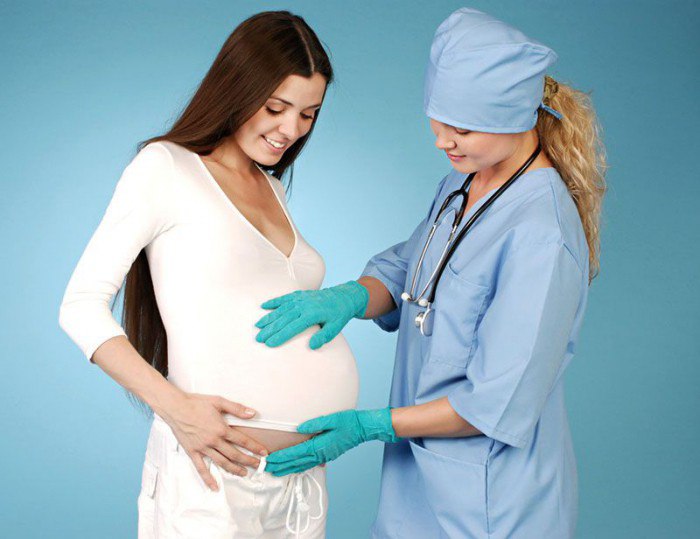 беременная и врач держит руки на ее животе