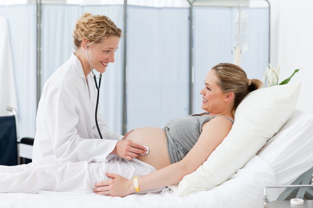 врач слушает беременную с помощью стетоскопа